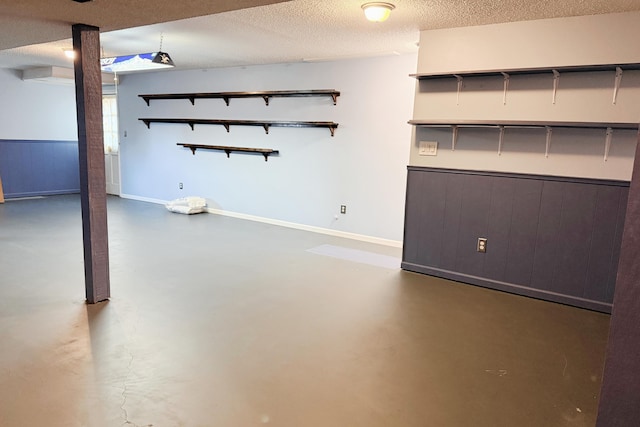 finished below grade area featuring a wainscoted wall and a textured ceiling