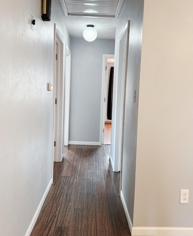 corridor featuring dark wood-style floors and baseboards