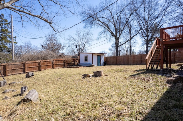 view of yard with a fenced backyard, stairway, a wooden deck, and an outdoor structure