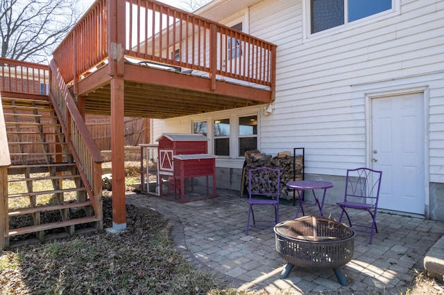 view of patio with stairway, fence, a deck, and an outdoor fire pit