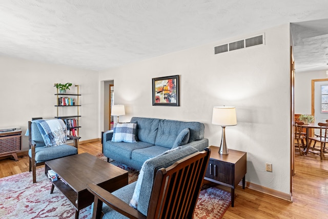 living area with baseboards, visible vents, and light wood finished floors