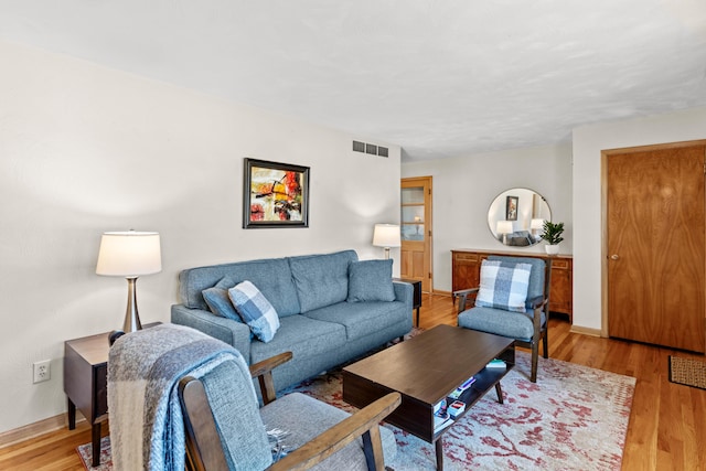 living area with light wood-style flooring, visible vents, and baseboards