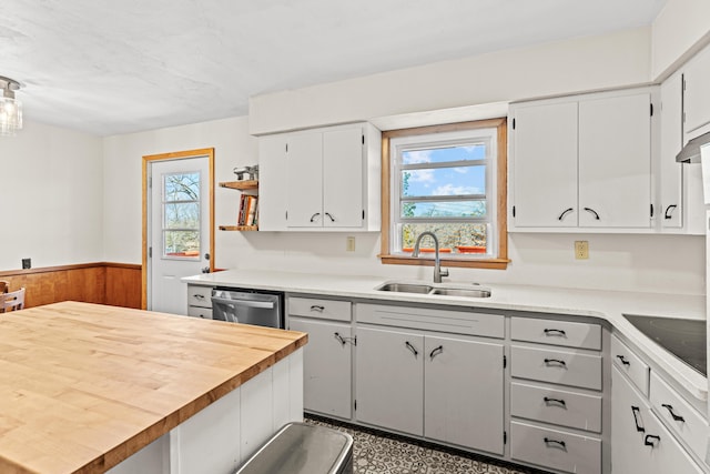 kitchen with open shelves, a sink, wainscoting, dishwasher, and black electric stovetop