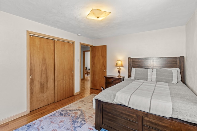 bedroom with a closet, baseboards, and wood finished floors