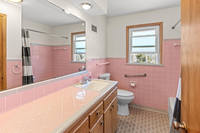 full bathroom featuring vanity, visible vents, tile patterned floors, toilet, and tile walls