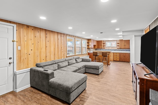 living room featuring recessed lighting, light wood-style floors, and wood walls