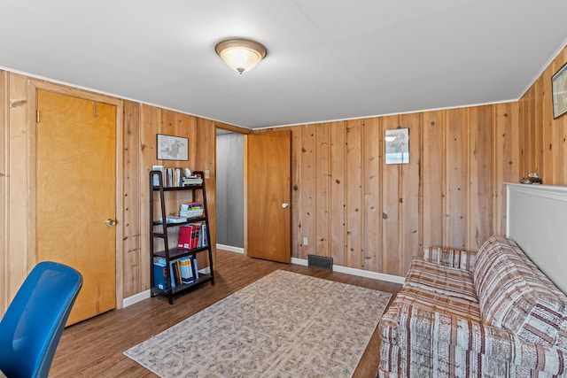 living area with visible vents, wood walls, baseboards, and wood finished floors