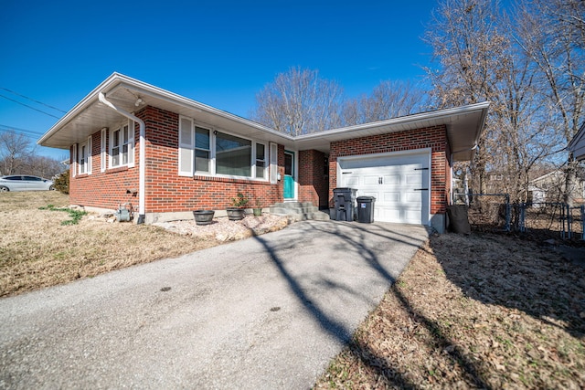 single story home featuring aphalt driveway, brick siding, an attached garage, and fence