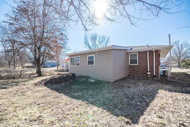 rear view of property featuring brick siding, a gate, and fence