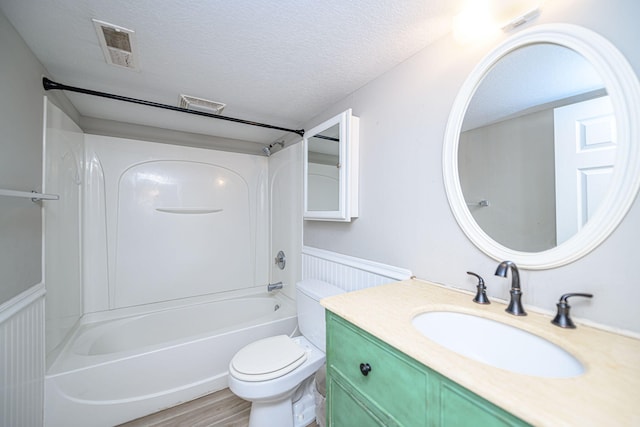 full bath featuring visible vents, shower / washtub combination, toilet, wainscoting, and a textured ceiling