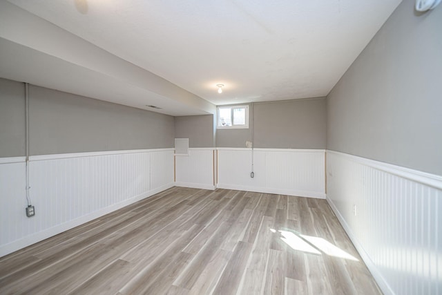 below grade area with a wainscoted wall and wood finished floors