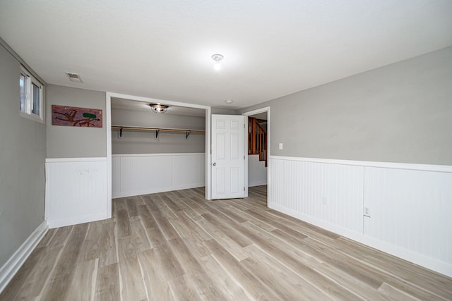 unfurnished room featuring visible vents, a wainscoted wall, and light wood finished floors