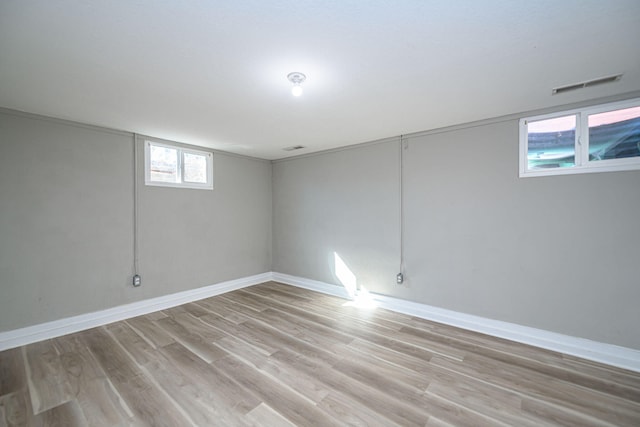 basement featuring visible vents, baseboards, and light wood finished floors