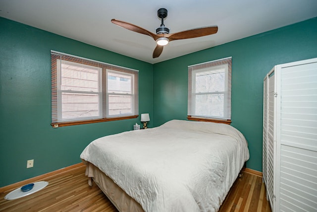 bedroom featuring multiple windows, baseboards, and wood finished floors