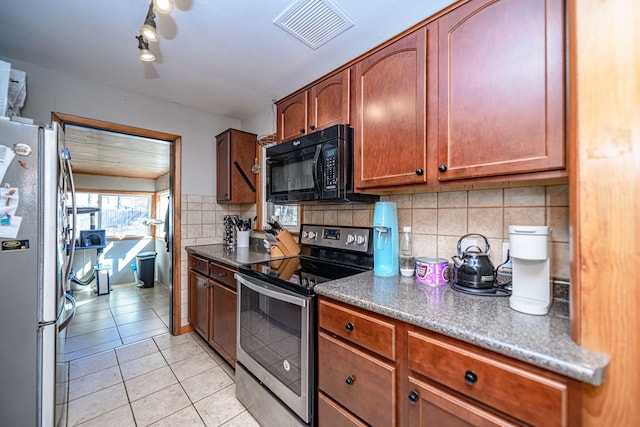 kitchen featuring dark countertops, visible vents, backsplash, appliances with stainless steel finishes, and light tile patterned flooring