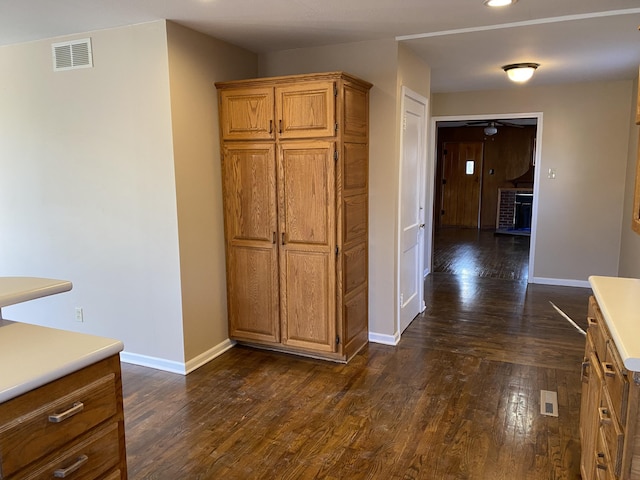 kitchen featuring visible vents, baseboards, dark wood finished floors, and brown cabinetry