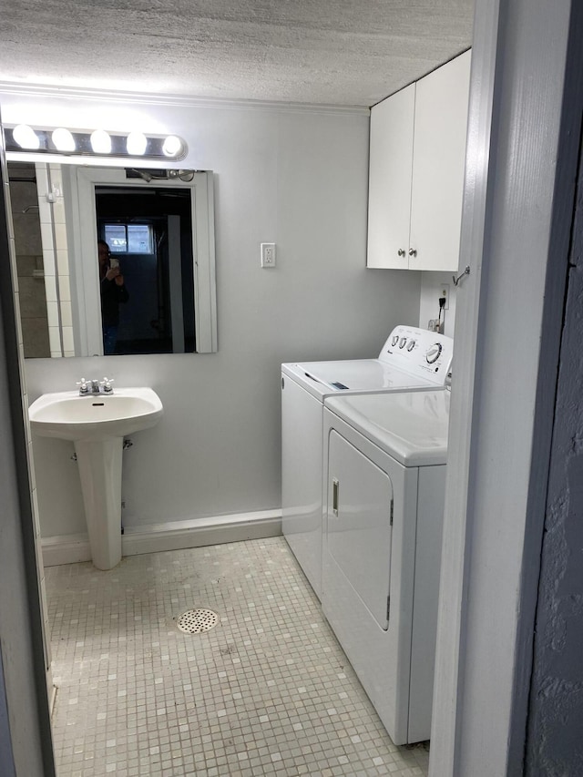 washroom with independent washer and dryer, a sink, a textured ceiling, light tile patterned floors, and baseboards