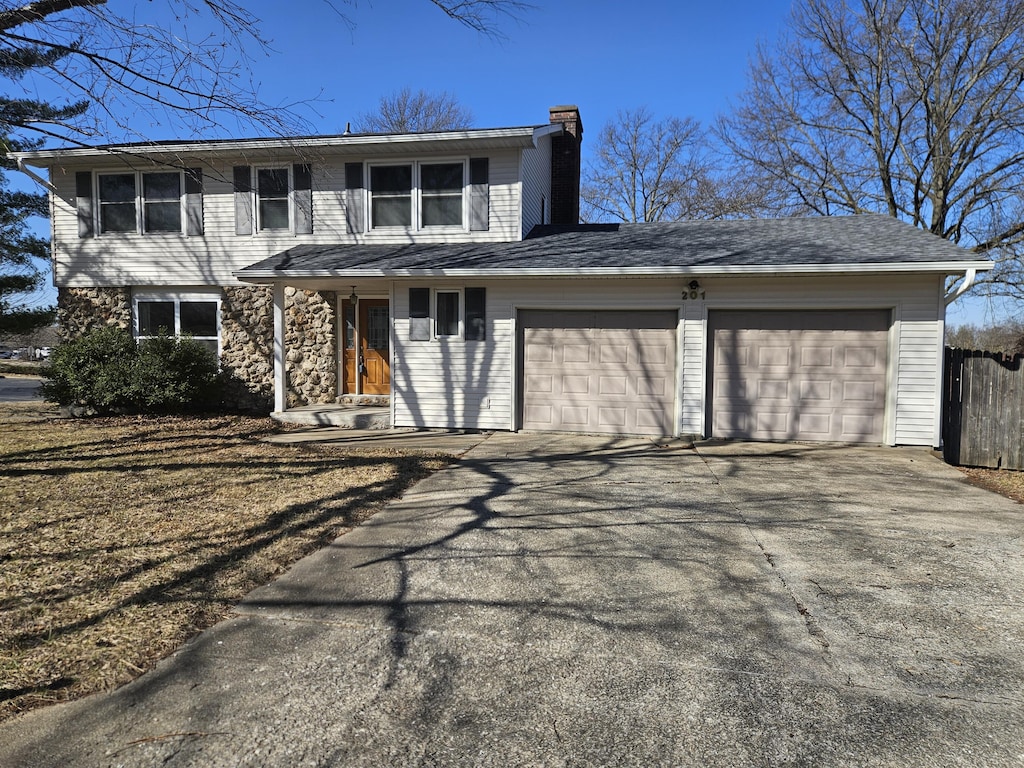 traditional-style house with an attached garage, fence, driveway, and a chimney