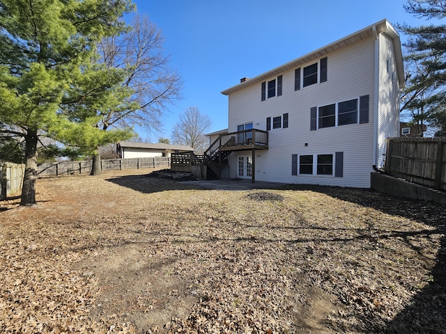 back of house featuring french doors, a chimney, a deck, and fence