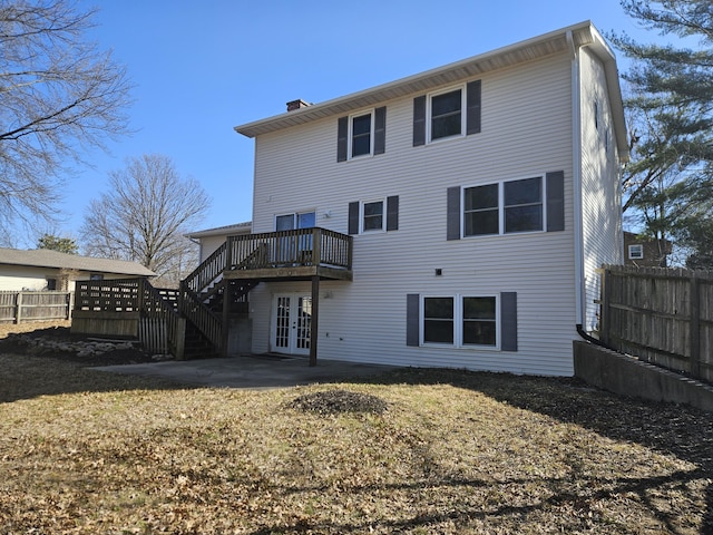 rear view of property featuring a deck, fence, french doors, stairway, and a chimney