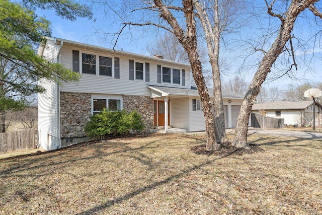 view of front of house featuring a front lawn, fence, a garage, and stone siding