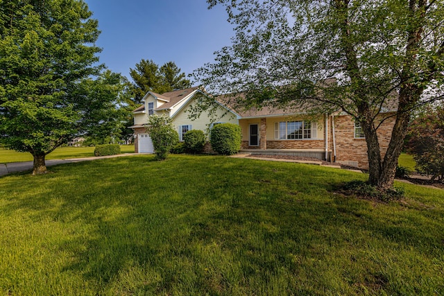 view of front of house featuring brick siding, a front lawn, and a garage