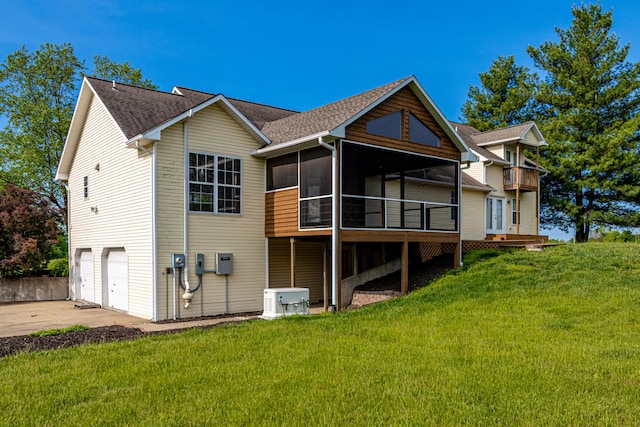 back of house with a lawn, an attached garage, concrete driveway, and a sunroom