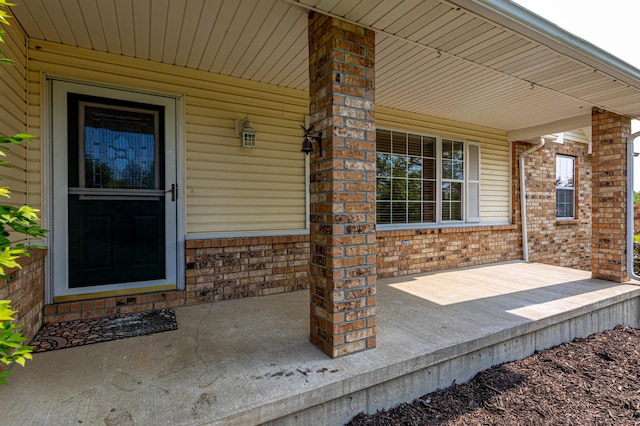 property entrance with brick siding and a porch