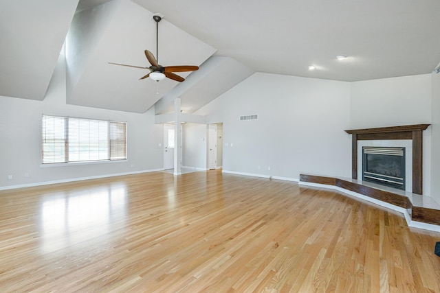 unfurnished living room with visible vents, a glass covered fireplace, light wood finished floors, baseboards, and ceiling fan