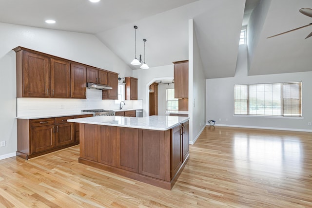 kitchen with light wood-style flooring, under cabinet range hood, open floor plan, arched walkways, and ceiling fan