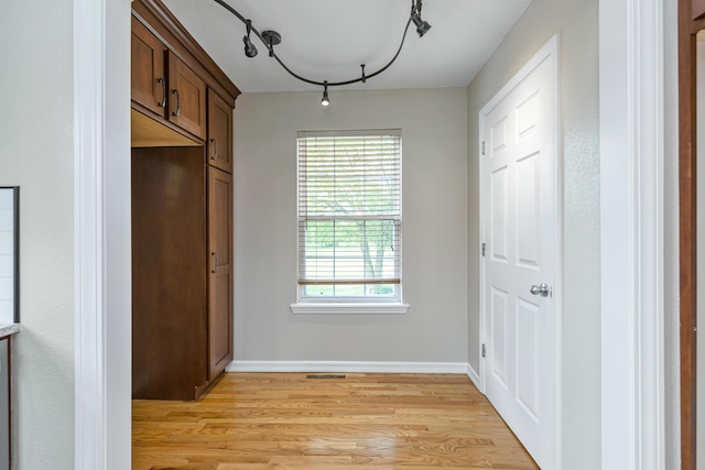 doorway to outside featuring visible vents, baseboards, track lighting, and light wood finished floors