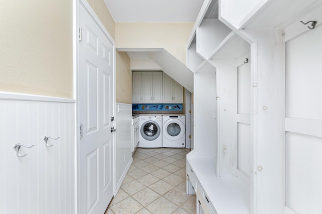 clothes washing area with cabinet space, light tile patterned flooring, wainscoting, and washing machine and clothes dryer