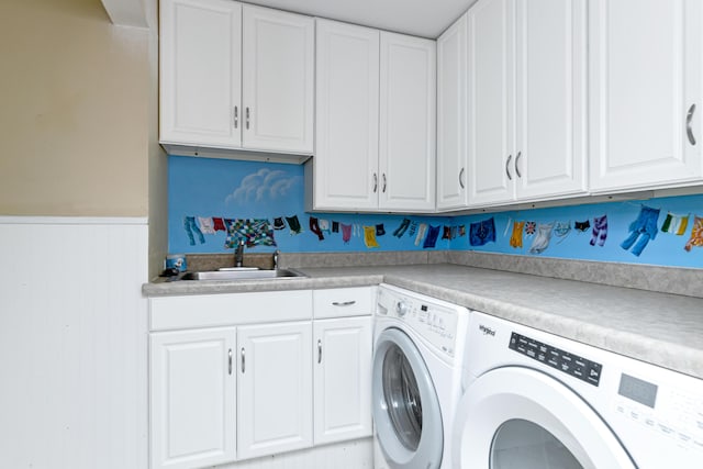 laundry room featuring cabinet space, a wainscoted wall, separate washer and dryer, and a sink