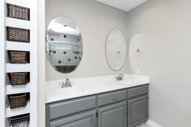 full bathroom with a sink, baseboards, a stall shower, and double vanity