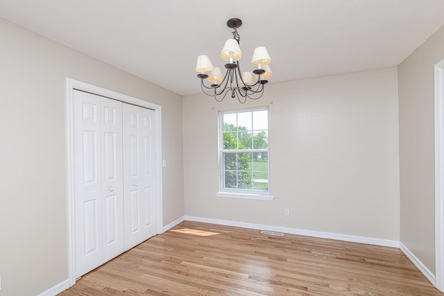 unfurnished dining area with light wood finished floors, a chandelier, visible vents, and baseboards