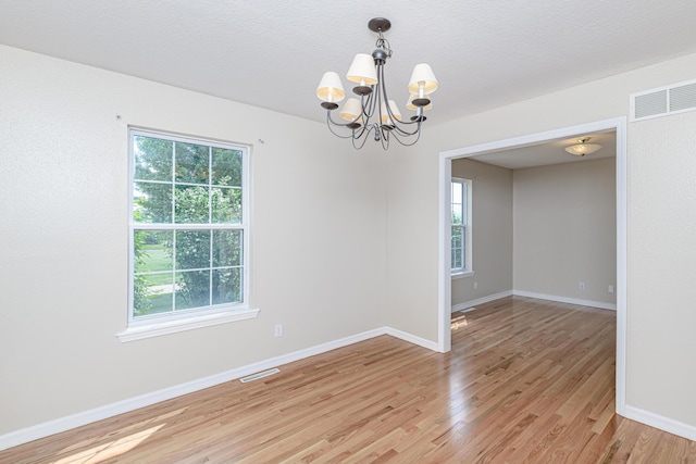 unfurnished room with visible vents, baseboards, light wood-style flooring, and a chandelier