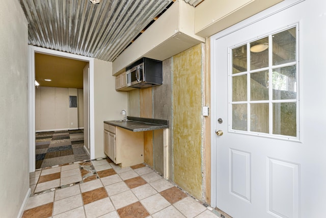 kitchen featuring a sink, stainless steel microwave, and dark countertops