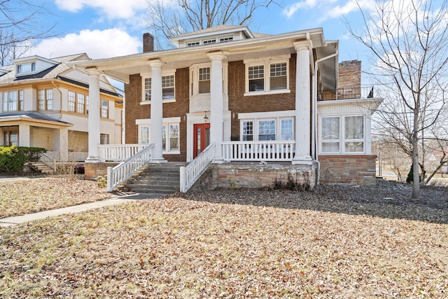 view of front of house with a porch, brick siding, and a chimney