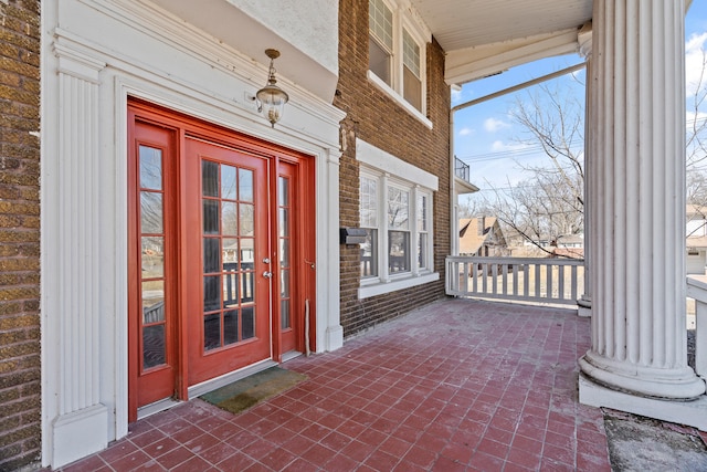 view of exterior entry featuring brick siding and a porch