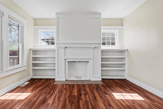 spacious closet featuring a brick fireplace, visible vents, and dark wood-style flooring