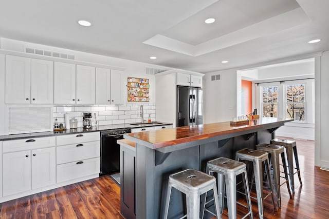 kitchen featuring visible vents, a sink, stainless steel fridge, a raised ceiling, and dishwasher