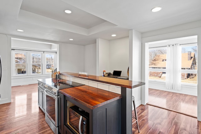 kitchen with electric range, butcher block counters, black microwave, and wood finished floors