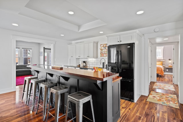 kitchen with butcher block countertops, plenty of natural light, a raised ceiling, and freestanding refrigerator