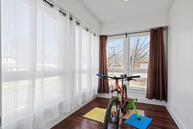 exercise room with baseboards and wood finished floors