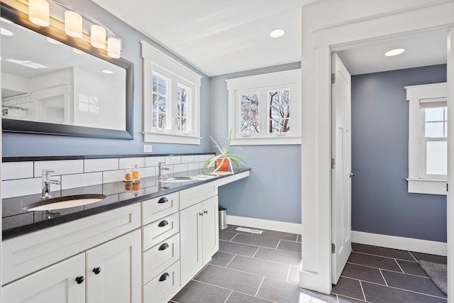 bathroom featuring tile patterned flooring, double vanity, baseboards, and a sink