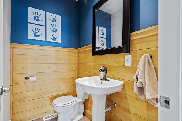 bathroom featuring visible vents, toilet, and wooden walls