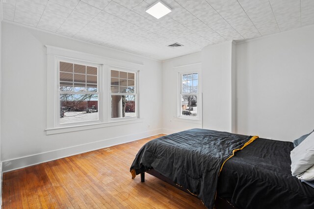 bedroom featuring visible vents, baseboards, and hardwood / wood-style floors