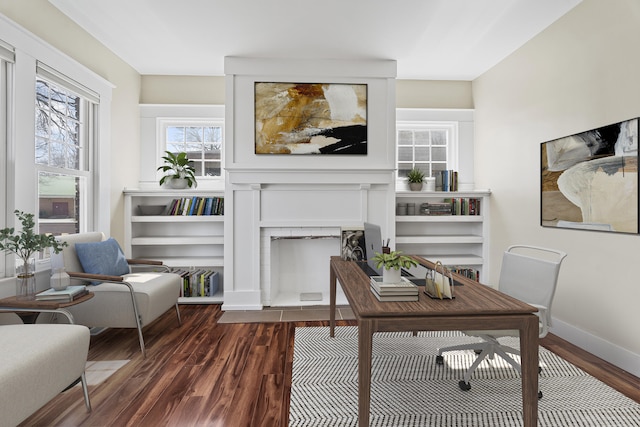 office space featuring baseboards, a fireplace with flush hearth, and wood finished floors