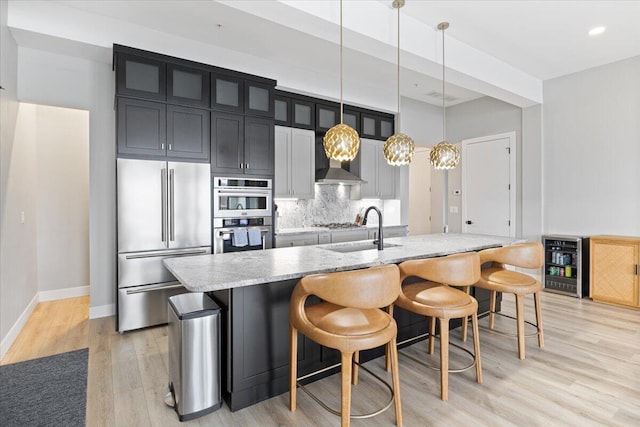 40 US Pl Unit 2B, Sunrise Beach, MO 65079 - kitchen featuring a breakfast bar area, beverage cooler, a kitchen island with sink, a sink, and appliances with stainless steel finishes