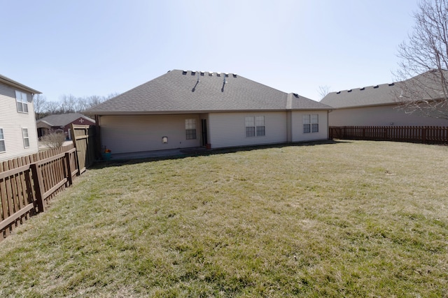 back of property with a yard, a fenced backyard, and roof with shingles